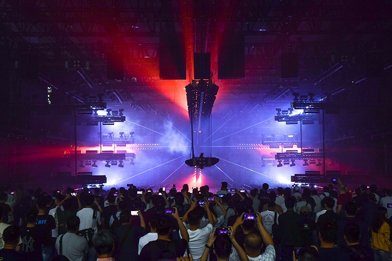 Large exhibition hall with light show, laser beams and audience filming the production