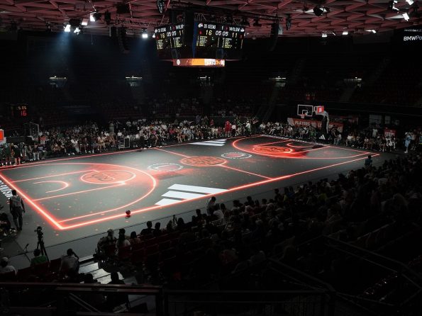 Ein LED-beleuchteter Basketballcourt mit Adidas-Branding und vollem Haus im BMW Park München.