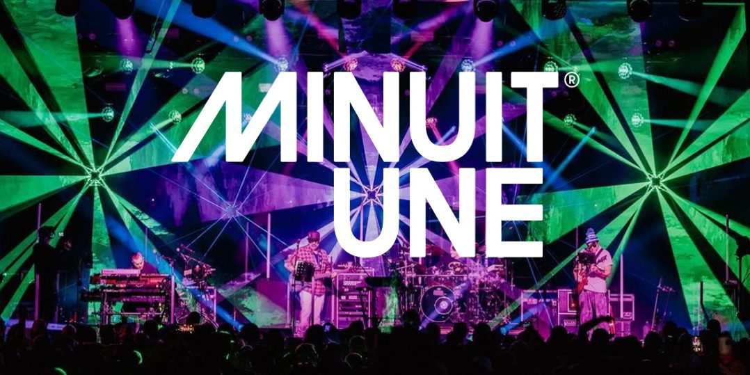 banniere-minuit-une Das Bild zeigt eine beeindruckende Live-Bühnenszene mit einer dynamischen Lichtshow. Der Hintergrund ist von intensiven grünen und violetten Lichteffekten geprägt, die strahlenförmig von verschiedenen Punkten ausgehen und den gesamten Raum einhüllen.
In der Mitte des Bildes befindet sich das große, weiße Logo von Minuit Une, das prominent über die Szene gelegt wurde. Auf der Bühne stehen mehrere Musiker, die von einer aufwendigen Lichtinstallation umgeben sind.
Die Beleuchtung erzeugt eine immersive Atmosphäre, die typisch für die IVL-Technologie von Minuit Une ist. Die Kombination aus multidirektionalen Lichtstrahlen, Projektionen und der energiegeladenen Live-Performance vermittelt den Eindruck eines intensiven, mitreißenden Konzerterlebnisses.