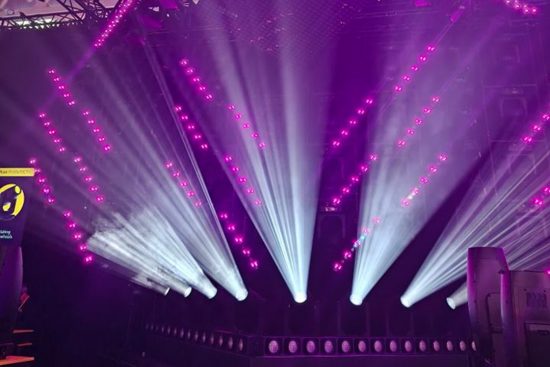 Violette und weiße Lichtstrahlen inszenieren eine Bühne mit dynamischen Effekten.
