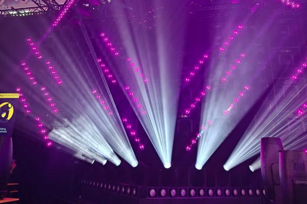 Violette und weiße Lichtstrahlen inszenieren eine Bühne mit dynamischen Effekten.