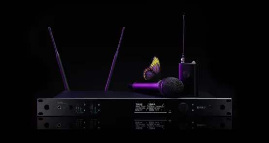Das Bild zeigt ein hochwertiges Drahtlossystem aus der DPA N-Serie Digital Wireless, bestehend aus mehreren Komponenten. Im Mittelpunkt steht ein N-DR1 Digital Wireless Receiver, ein professioneller Zweikanalempfänger mit zwei aufrecht stehenden Antennen, mehreren LED-Anzeigen und einem Display, das technische Informationen wie Frequenzen und Signalstärke darstellt. Auf dem Empfänger liegt ein kabelloses Handmikrofon, das zum DPA d:facto™-Sortiment gehören könnte. Rechts daneben steht ein Bodypack-Transmitter mit einer angeschlossenen Antenne, der eine kompakte und robuste Bauweise aufweist. Das gesamte Equipment ist in einem eleganten, schwarzen Design mit modernen, lila Akzenten gehalten. Besonders auffällig ist ein Schmetterling, der auf dem Mikrofon platziert ist. Dies könnte symbolisch für die klare und natürliche Klangqualität der DPA-Produkte stehen. Der Hintergrund ist tiefschwarz, was das Equipment in den Fokus rückt und die hochwertige Ästhetik der Produktreihe unterstreicht.