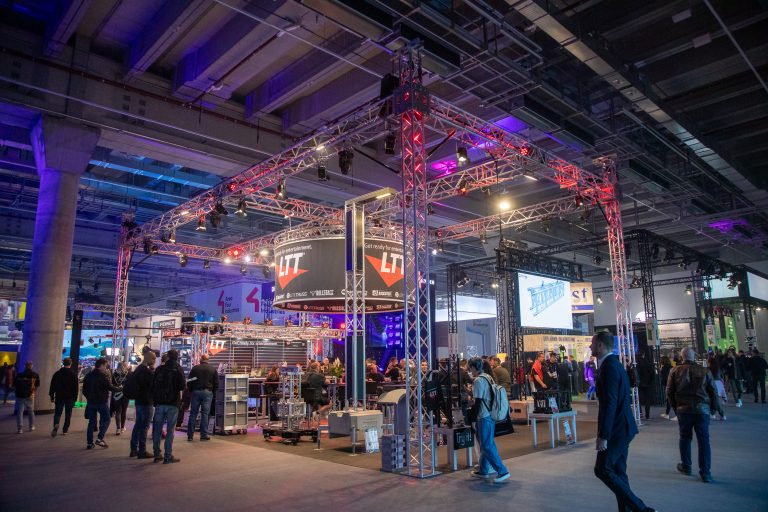 Menschen auf der Prolight + Sound Messehalle an einem beleuchteten Messestand von LTT