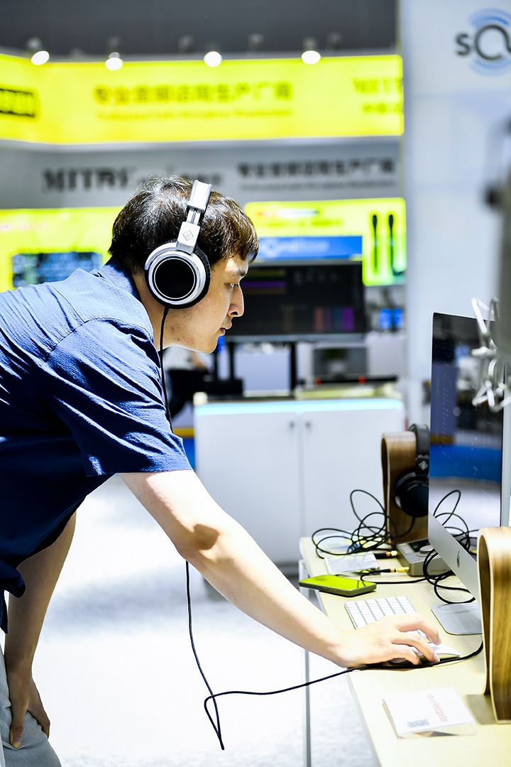 Visitor testing headphones at an audio booth at the trade fair