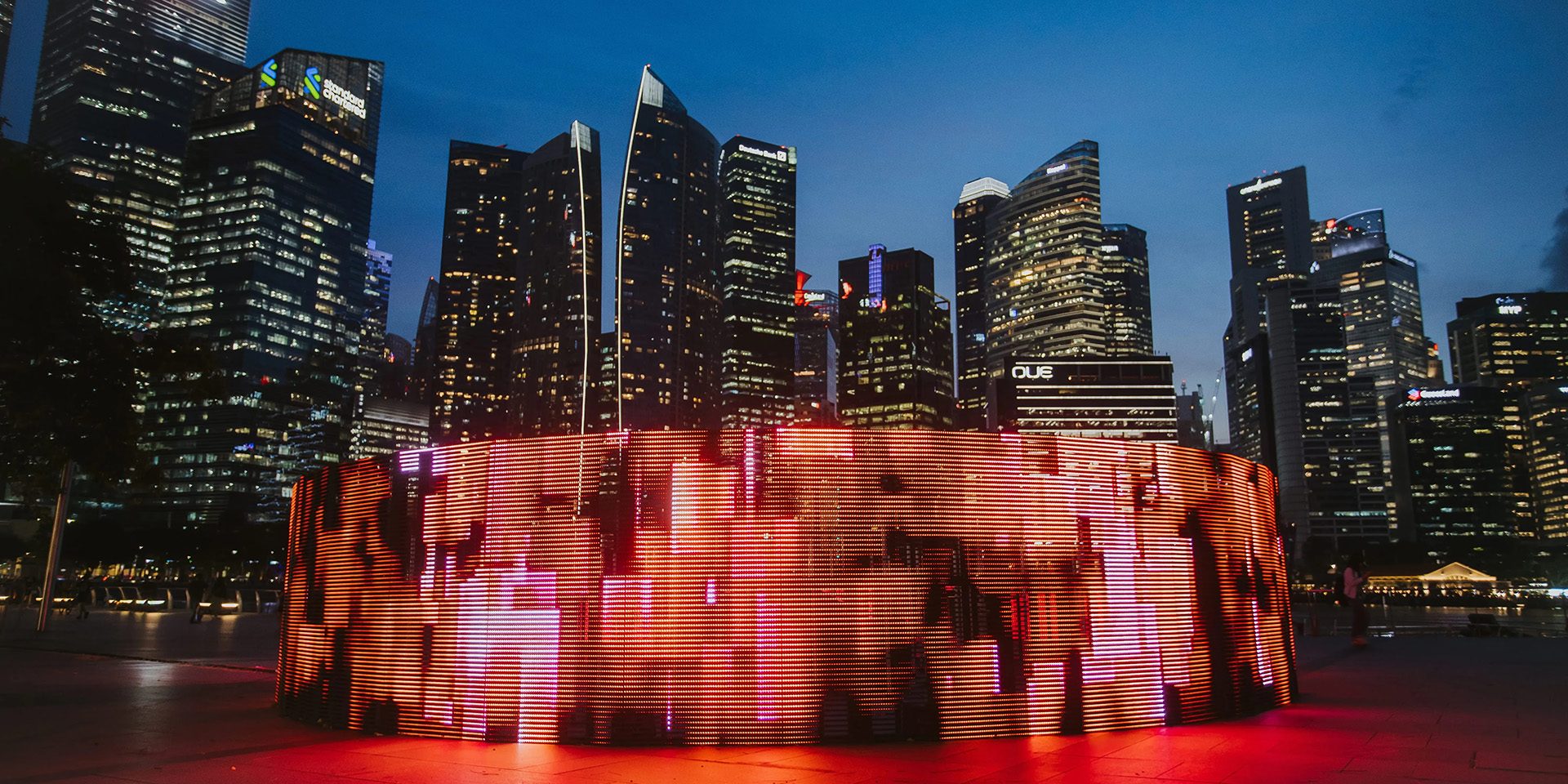 Leuchtende Lichtinstallation vor der nächtlichen Skyline von Singapur