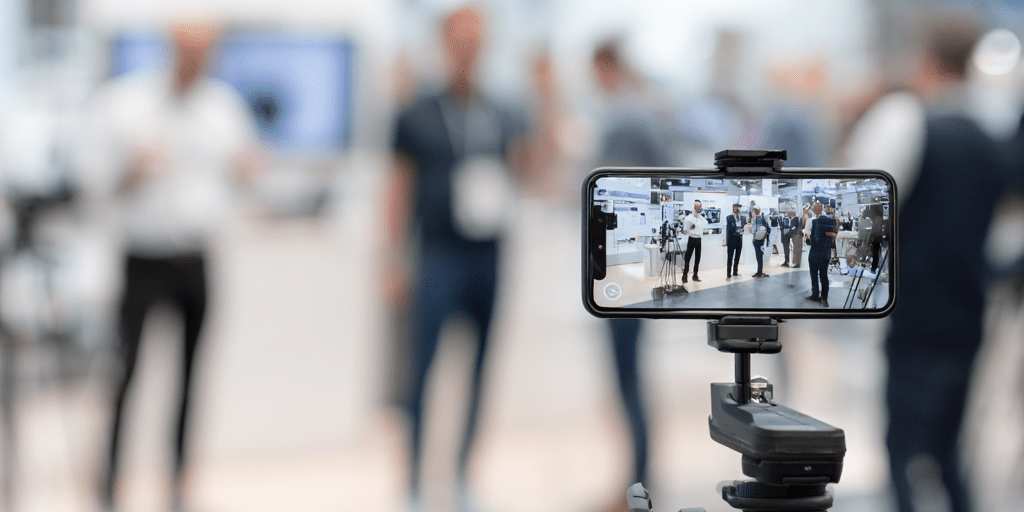 Wie Influencer das Event-Streaming revolutionieren – neue Chancen für Veranstalter Smartphone auf Stativ filmt Event für Streaming mit Influencern in moderner Messehalle