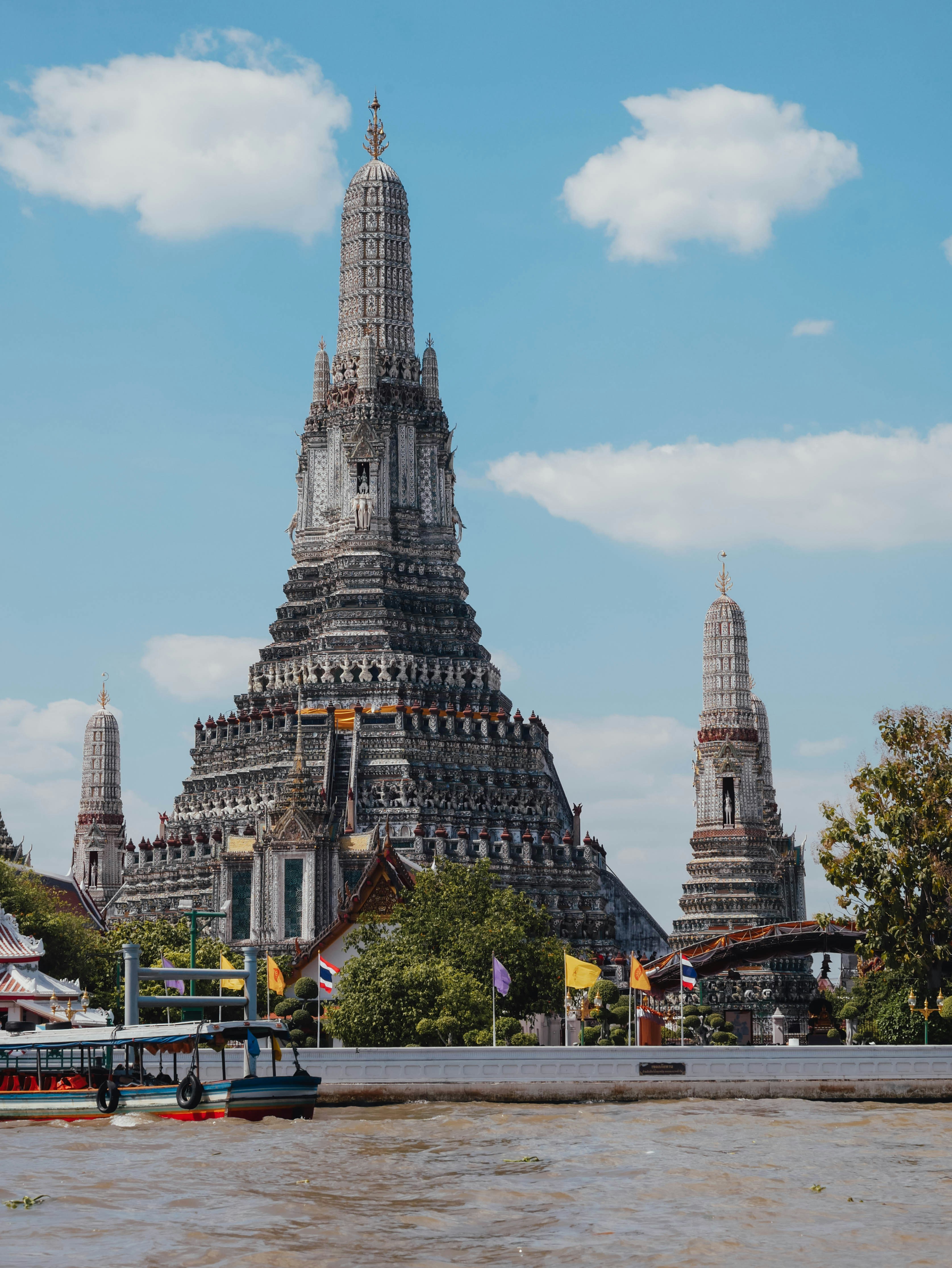 Wat Arun am Chao Phraya in Bangkok mit Boot und blauem Himmel.