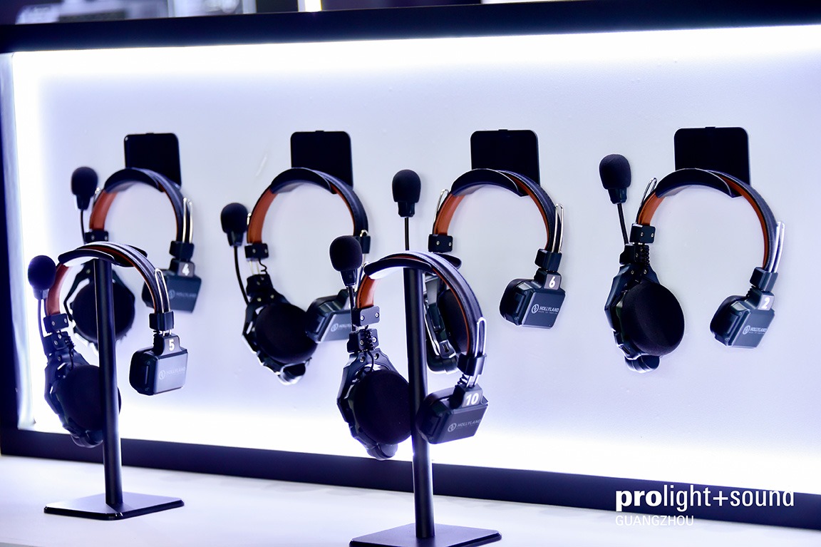 Several headsets with microphones are on display against an illuminated wall