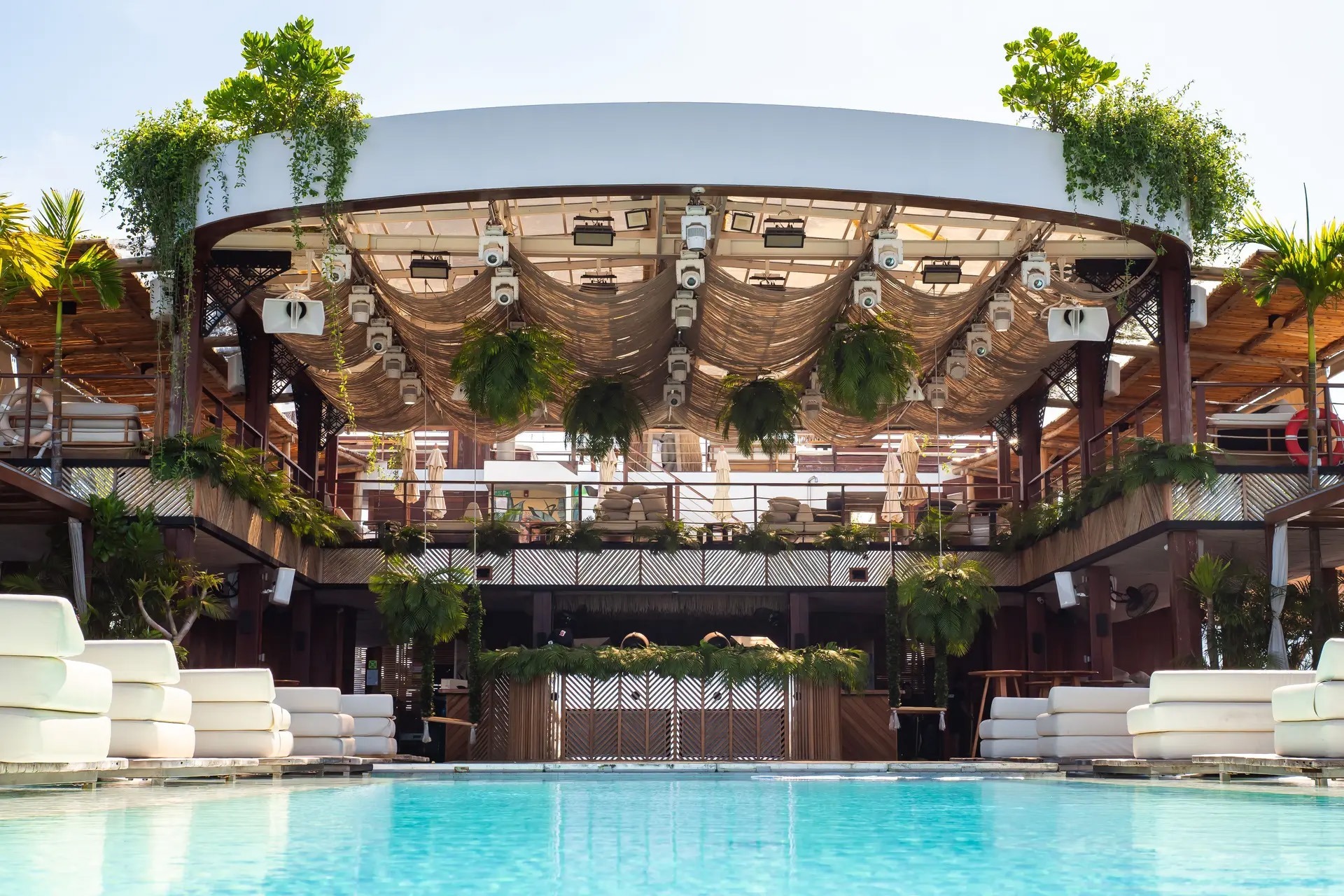 Tropischer Beachclub mit Pool, Palmen und integrierten weißen Lautsprechern