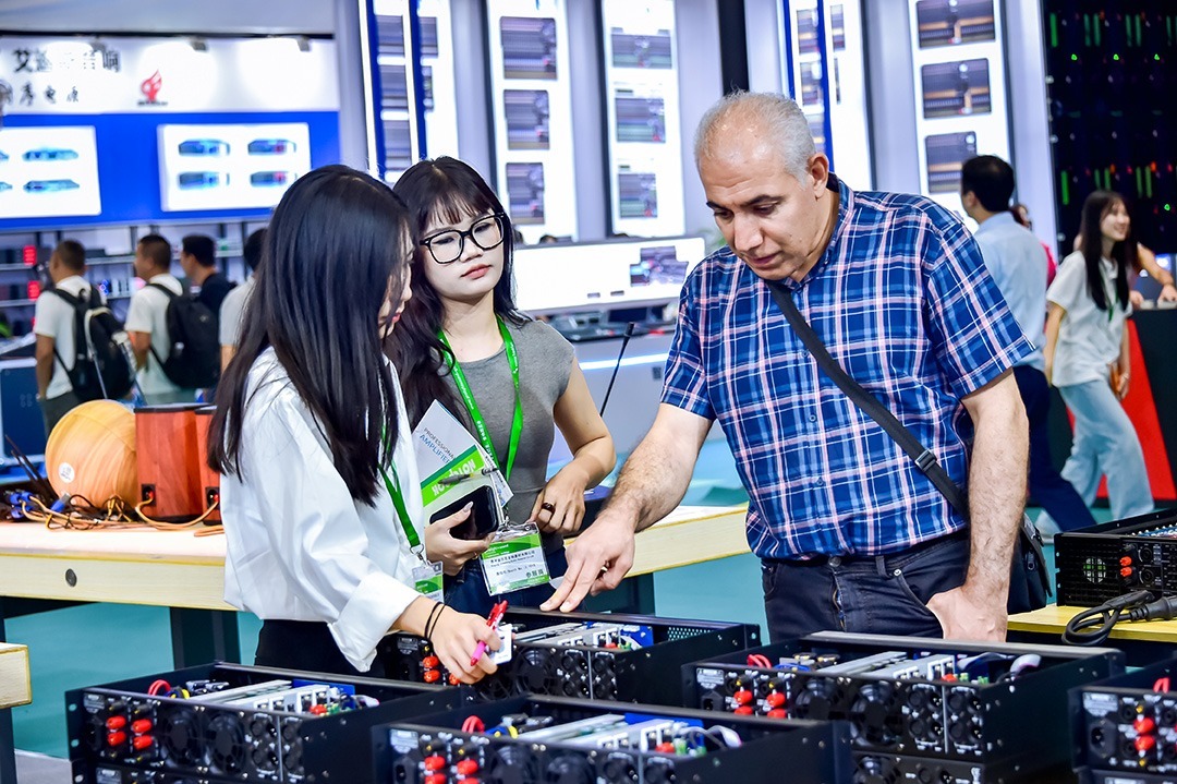 Besucher und Aussteller besprechen Technikdetails an geöffneten Geräten am Messestand