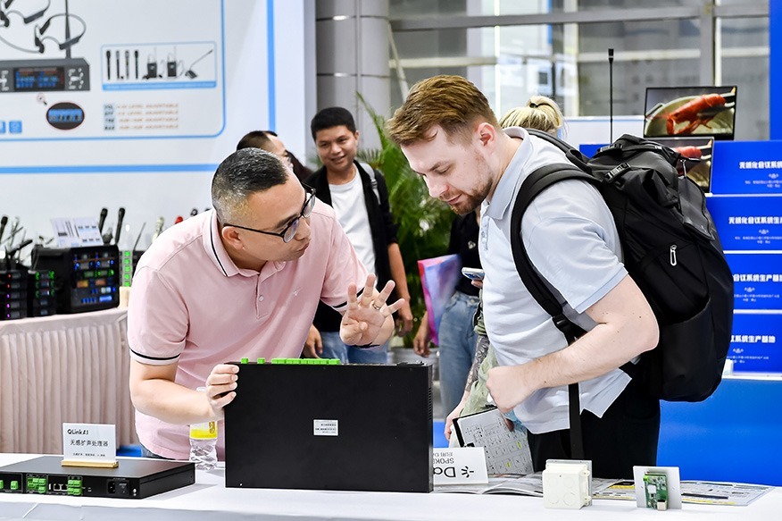 Zwei Besucher diskutieren Technik am Messestand, Produktdemo im Fokus