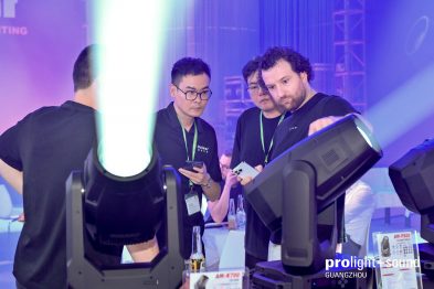 Fachbesucher begutachten leuchtende Moving Heads am Messestand
