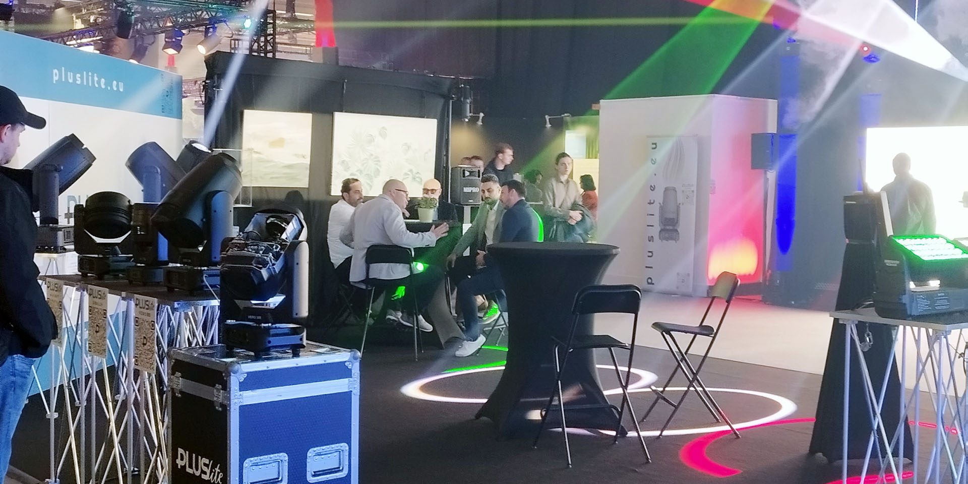 PLUSlite Prolight + Sound 2025 Messestand von Pluslite mit Scheinwerfern, Lichtstrahlen und Besuchergruppe in Gesprächen.