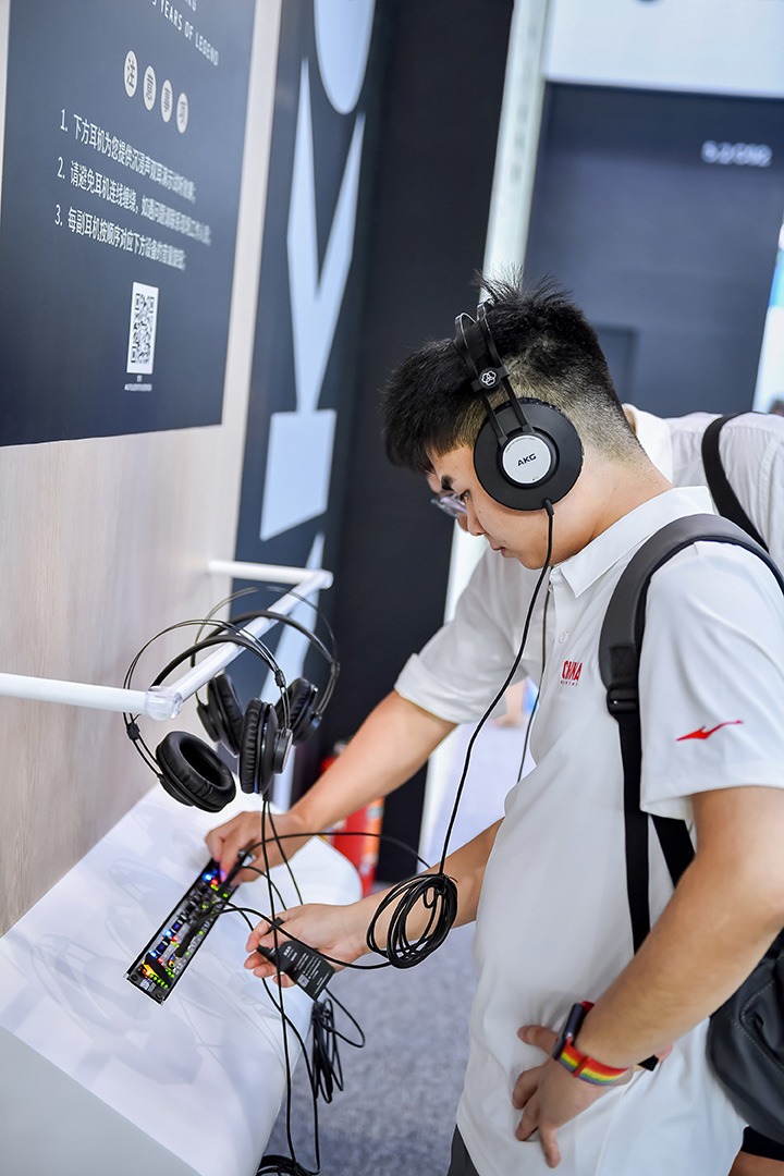 Besucher testet Kopfhörer und Audiointerface an einem Messestand