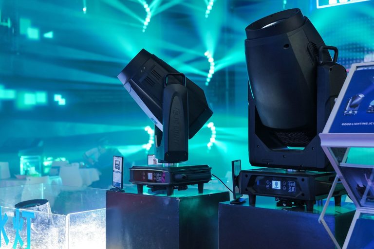pro-light-exhibitor-plsb Professionelle Moving Lights erzeugen türkisfarbene Lichtstrahlen in einer Veranstaltungshalle.
