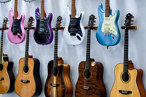 Several acoustic and electric guitars hang neatly on a wall.