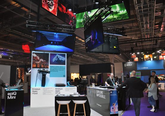 Messestand von Tait mit epiQ Mini Console, Bildschirmen und Besucherinnen und Besuchern auf Messe.