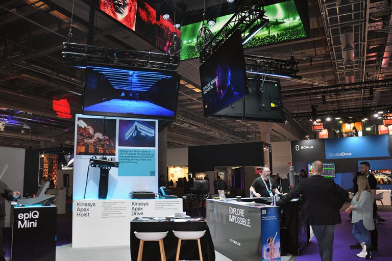 Messestand von Tait mit epiQ Mini Console, Bildschirmen und Besucherinnen und Besuchern auf Messe.