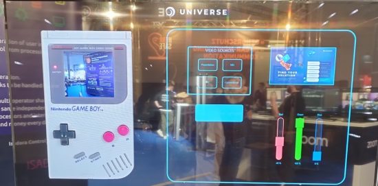 Das Bild zeigt ein interaktives Setup, das Retro-Technologie und moderne Steuerung kombiniert. Links ist ein Nintendo Game Boy zu sehen, dessen Bildschirm ein aktuelles Bild anzeigt, was auf eine kreative Nutzung als Interface hinweist. Rechts wird eine futuristische Benutzeroberfläche präsentiert, die verschiedene Bedienelemente umfasst, darunter Videoquellen-Auswahl und Schieberegler für Farbanpassungen (Rot, Grün, Blau) mit Prozentwerten. Im oberen Bereich ist eine Werbe- oder Infografik mit dem Slogan „Find Your Solution“ eingebettet. Der Hintergrund deutet auf eine Messe oder Ausstellung hin, mit Besuchern und einem Stand, der die Interaktion zwischen Technologie und Kreativität hervorhebt.